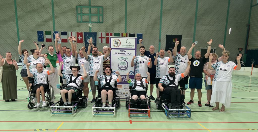A group of powerchair football players celebrating